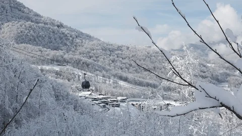 Aerial view over snowy mountain ridge valley with clouds, cable car lifting. 스톡 동영상 101537815