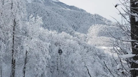 Aerial view over snowy mountain ridge valley with clouds, cable car lifting. 스톡 동영상 101538229