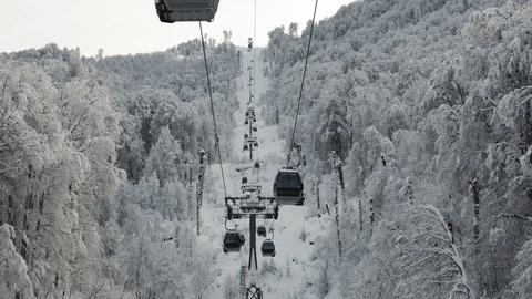 Aerial view over snowy mountain ridge valley with clouds, cable car lifting 스톡 동영상 101538870