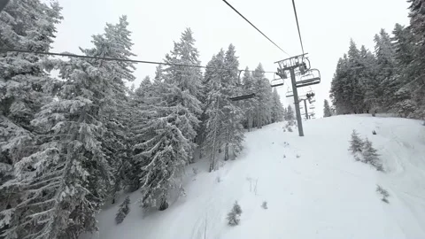 Aerial view over snowy mountain winter forest with chair lift at ski resort Stock Footage 196615871