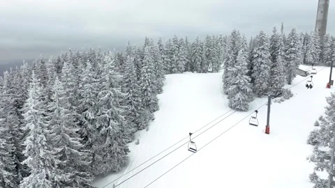Aerial view over snowy mountain winter forest with chair lift at ski resort Stock Footage 248027341