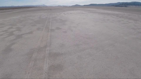 Aerial view over tire tracks across a dry desert landscape Stock Footage 92371853