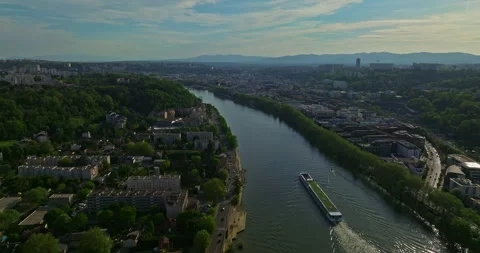Aerial view over town at sunset along a blue river. A tourist ship moves along Stockbeeldmateriaal 274491375