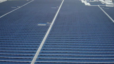 Aerial view over trees around snow covered solar cells with factory background Stock Footage 218450494