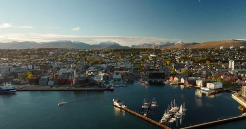 Aerial view over Tromso harbor with docked boats and snowy mountain peaks Vídeo Stock 321731993