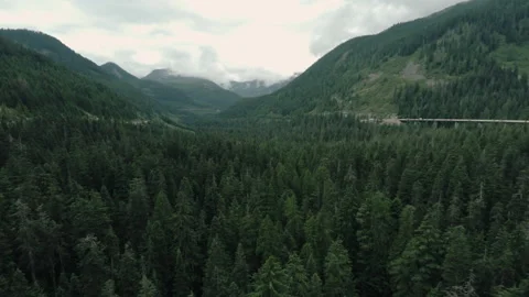Aerial view over a valley forest and mountain highway Vidéo 154922936