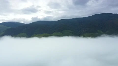 Aerial view over valley surrounded by mountains and covered with fog and mist Stock Footage 140401436