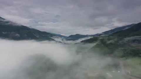 Aerial view over valley surrounded by mountains and covered with fog and mist Stock Footage 140401627