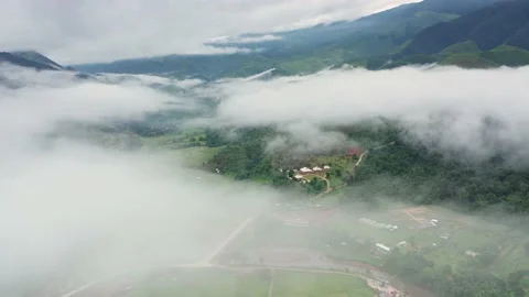 Aerial view over valley surrounded by mountains and covered with fog and mist Stock Footage 140401885