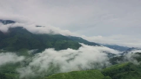 Aerial view over valley surrounded by mountains and covered with fog and mist Stock Footage 140402220