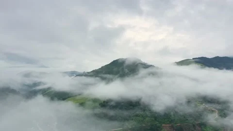 Aerial view over valley surrounded by mountains and covered with fog and mist Stock Footage 141522519