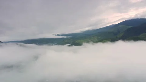 Aerial view over valley surrounded by mountains and covered with fog and mist Stock Footage 141523181