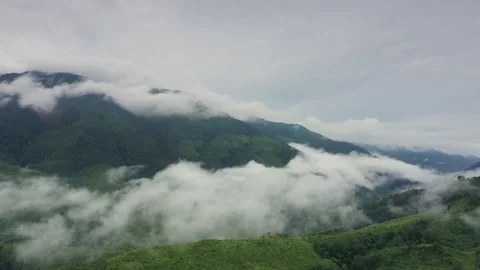 Aerial view over valley surrounded by mountains and covered with fog and mist Stock Footage 141928444