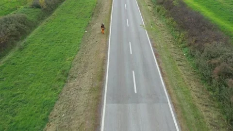 Aerial view over worker in protective clothing as mowing grass around traffic Vidéo 318001589