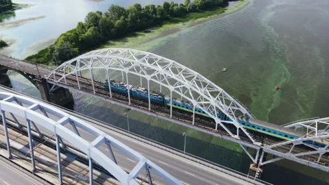 Aerial view of the overground train passing over the bridge over the river Stock Footage 164595272