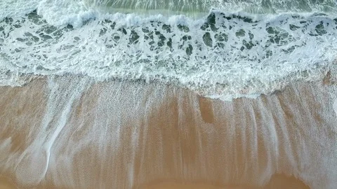 Aerial view overhead of white waves crashing on empty sandy beach in summer Stock Footage 95123530
