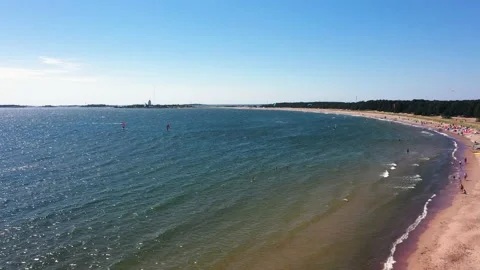 Aerial view overlooking paragliders, outside a beach, while people is Vídeo Stock 140160512