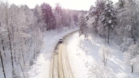 Aerial view overlooking a road, in middle of snow covered trees and snowy forest Video stock 153014581