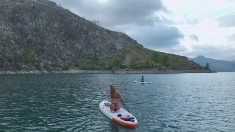 Aerial View: Paddleboarders explore stunning waters with a dramatic backdrop of Stock-Footage 296192485