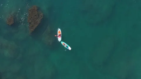 Aerial view of paddling boards, two people paddling in green sea Stock Footage 344729360