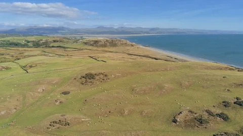 Aerial view, pan move. Drone panorama over grass, beach, sea with Criccieth c Stock Footage 94241523