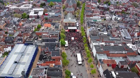 Aerial view panning down on Kings day crowd in the Fish market of Groningen. Video stock 188144341
