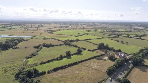 Aerial view, panning move. Double line road, houses and fields on Cheshire co Stock Footage 95565115