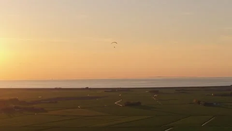 Aerial view of paramotor gliding over farmland at sunset, Netherlands Stock Footage 313364613
