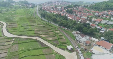 Aerial View of Passenger Train Passing by a Curved Rail and Rice Field Stock Footage 131102525
