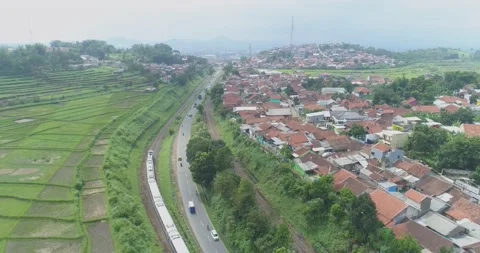 Aerial View of Passenger Train Passing by a Curved Rail and Rice Field Stock Footage 131102994