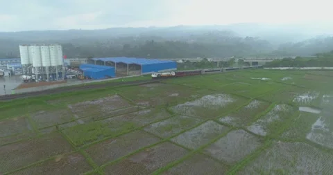 Aerial View of Passenger Train Passing by a Curved Rail and Rice Field Stock Footage 131111247