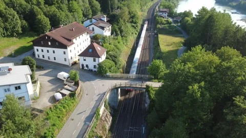 Aerial view of a passenger train passing under a bridge by the Inn river Vidéo 340004785