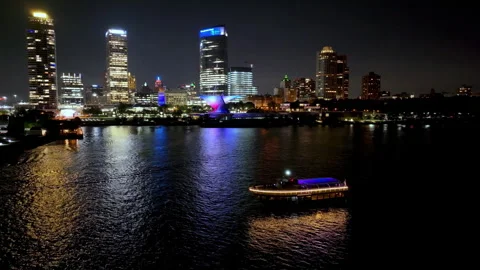 Aerial view passing a ferry in front of the skyline of Milwaukee, night in USA Stock Footage 323777700
