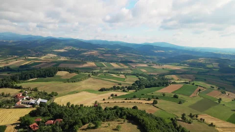 Aerial view of patchwork of agricultural fields, woods and mountains in cloudy Stock Footage 261827871