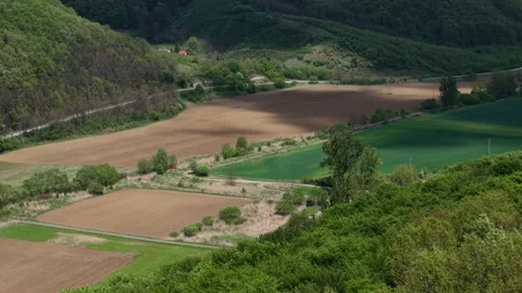 An aerial view of patchwork agricultural fields nestled among rolling green Stock-Footage 335222204