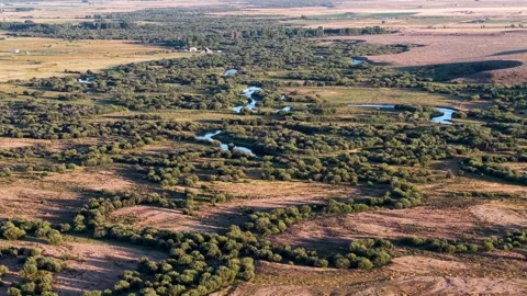 An aerial view of a patchwork landscape featuring grassy meadows, wetlands, and Stock Footage 328601352