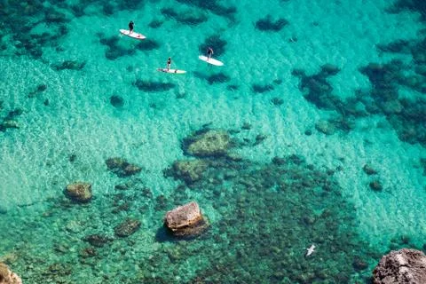 Aerial view of people padding on SUP (stand up paddle) on crystal clear blue  Stock Photos