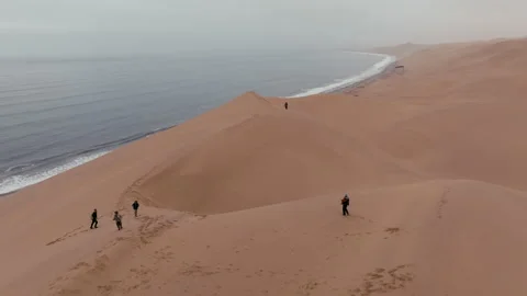 Aerial View Of People Walking On Namibia Sand Dunes By The Ocean Stock Footage 347126933