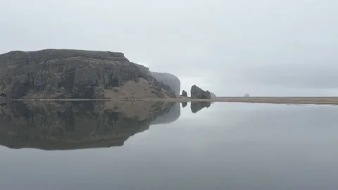 Aerial view, perfect reflection on black sand beach behind Dyrholaey Video stock 239523142