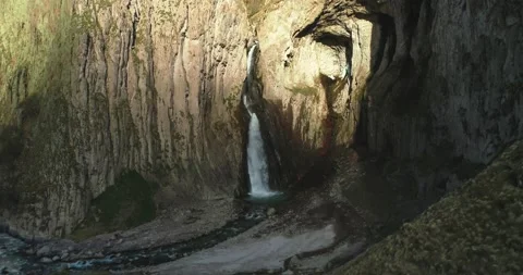 Aerial view of a picturesque waterfall between rocks in a mountain gorge Stock Footage 157728163