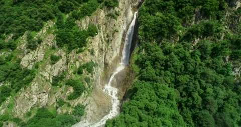Aerial view of a picturesque waterfall between rocks in a mountain gorge Stock Footage 157731447