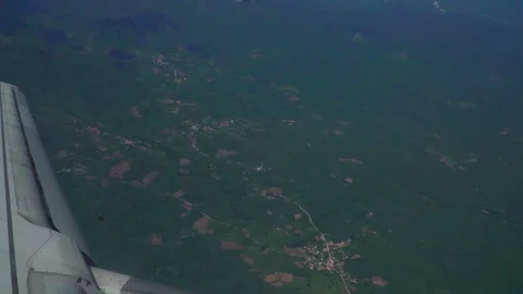 Aerial view of plane flying over small town surroundes by green hills Stock Footage 109502153