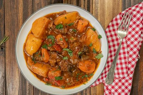 Aerial view of a plate with homemade meat, potato and vegetable stew on a woo Stock Photos