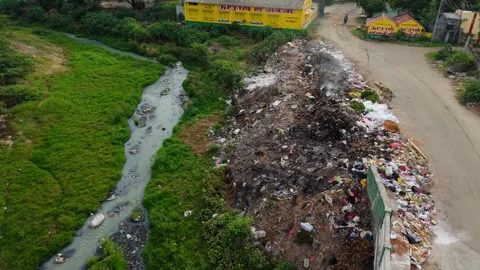 Aerial View of Polluted River Stream with Garbage Dumping Along Banks in Urban Stock Footage 316723029
