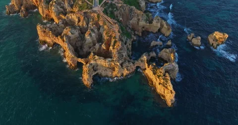 Aerial view of the Ponta da Piedade lighthouse surrounded by cliffs, boats, and Stock-Footage 312274232