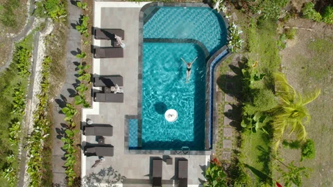 Aerial view of a pool surrounded by greenery, with a single woman swimmer Video stock 289480866
