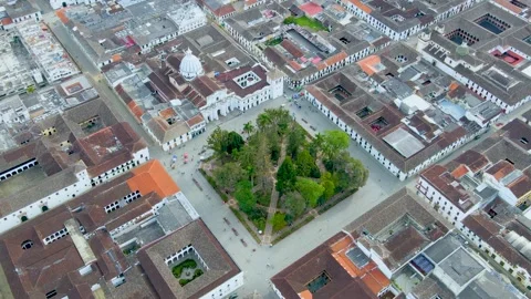 Aerial view of Popayán plaza with tree-filled square and white church dome Stock Footage 331254591