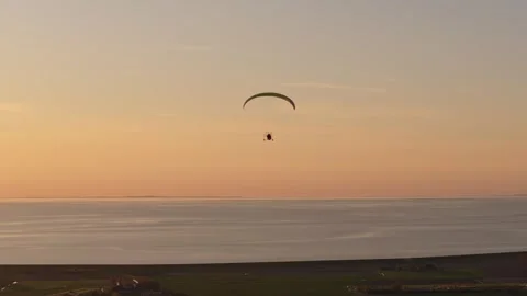 Aerial view of powered paraglider soaring above fields in Dutch twilight Stock Footage 313364404