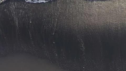 Aerial view powerful ocean waves at black volcanic beach crashing and foaming. Stock Footage 130363782