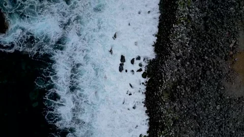 Aerial view of powerful ocean waves crashing onto a dark rocky shore, creat.. Stock Footage 324506162